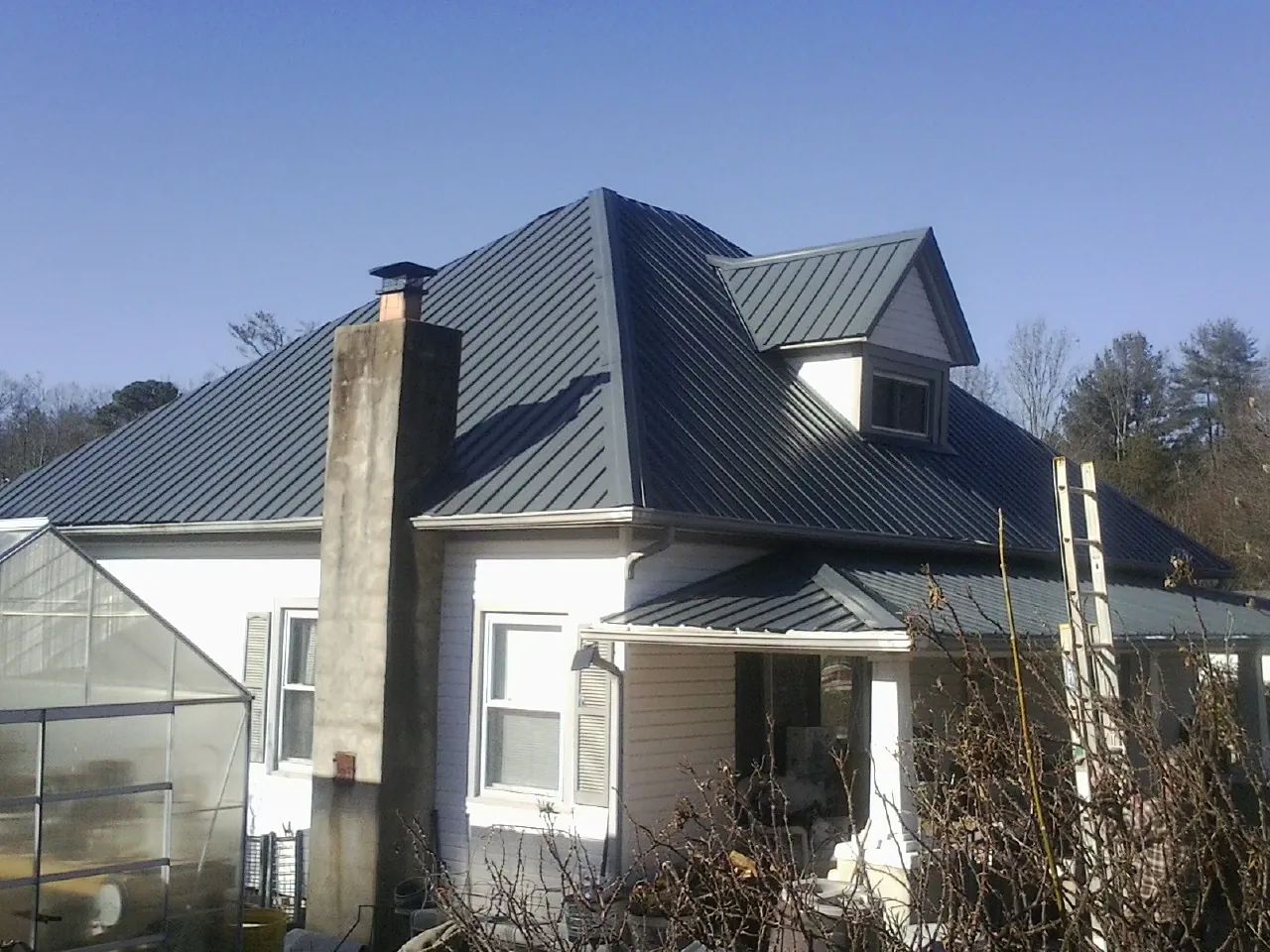 Dark blue standing seam metal roof on a white farmhouse with dormer — Slate & Tile Roof Repair by Roofing Brothers in Aumsville