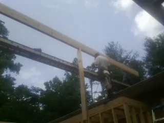 Carpenter setting a ridge beam over a new addition frame — Ice Dam Removal by Roofing Brothers in Aumsville