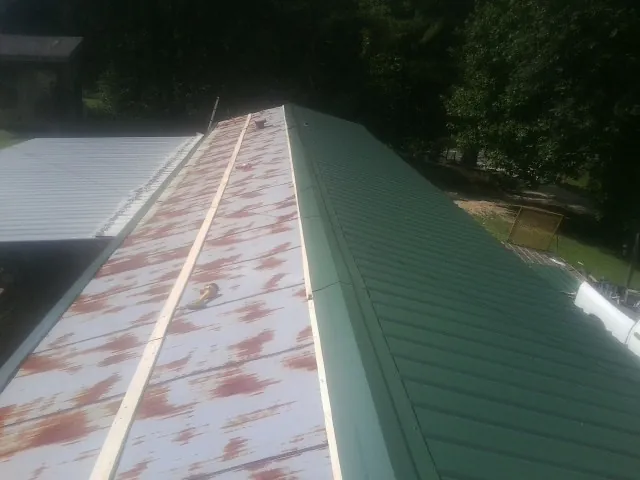 Old rusted panels beside newly installed green metal roofing — Wind Damage Roof Repair by Roofing Brothers in Aumsville
