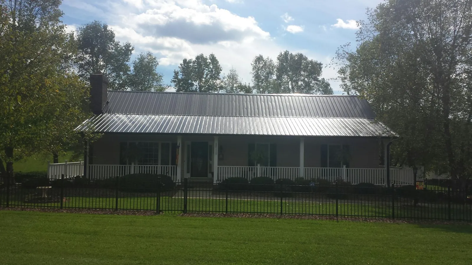 Gray metal roof on a brick ranch with a full width front porch — Gutter Guard Installation work by our crew in Aumsville