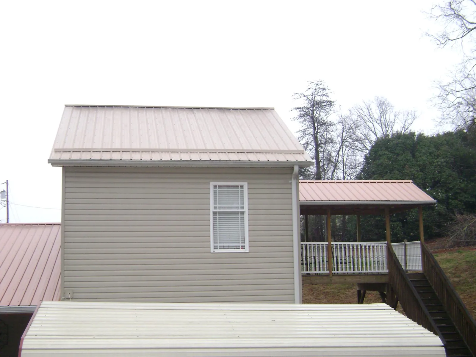 Tan metal roofs on a two story addition and attached porch, from a Roof Replacement job in Aumsville