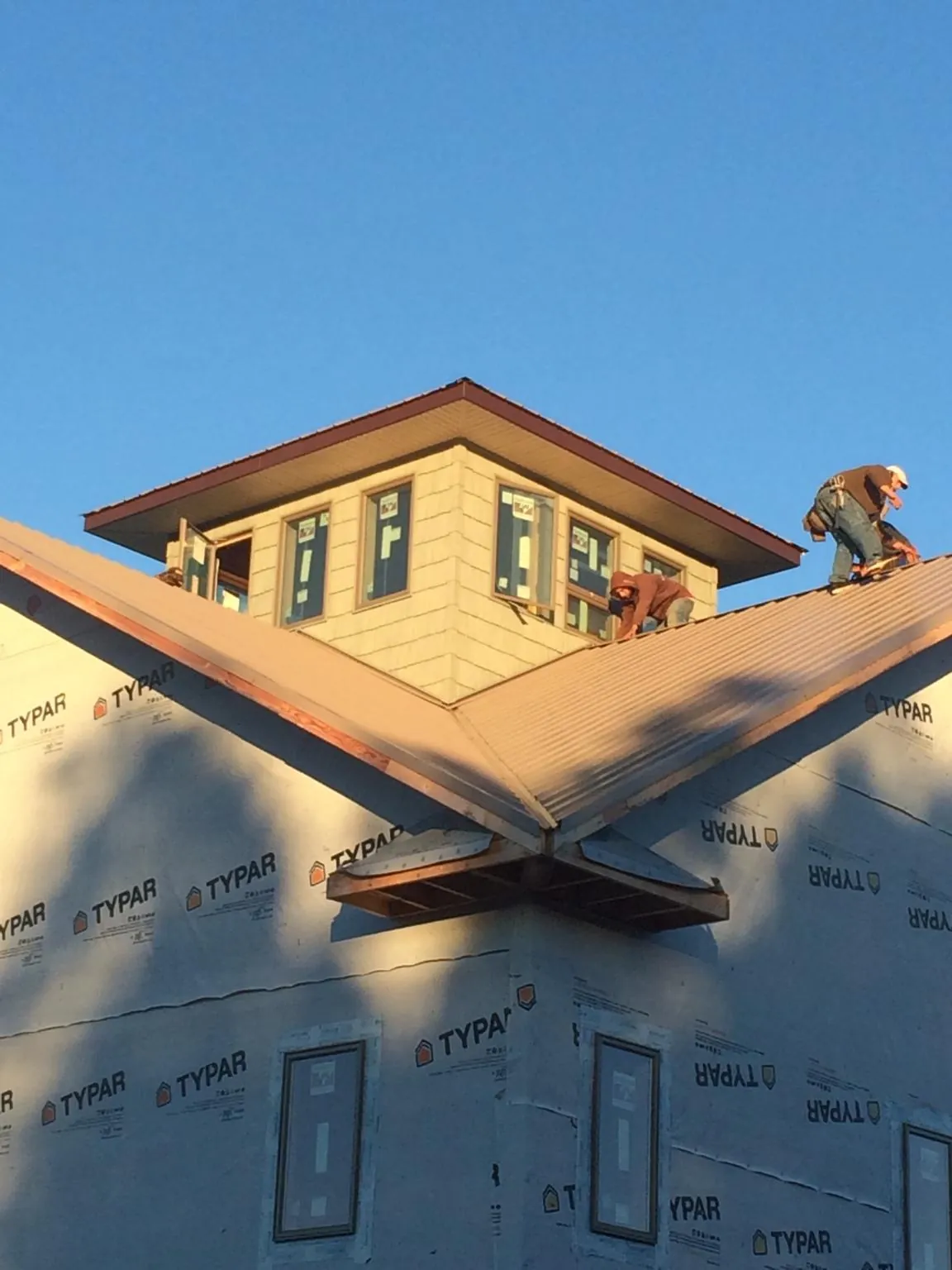 Roofers working around a rooftop cupola on a new metal roof at sunset — Roof Waterproofing in Aumsville by Roofing Brothers